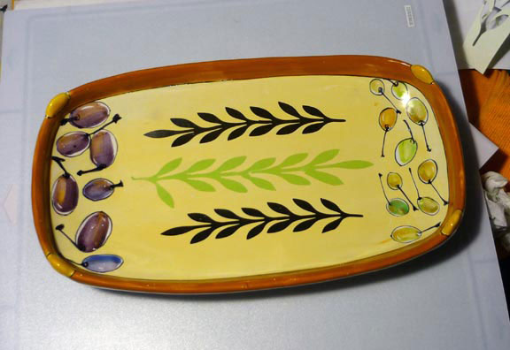 Majolica tray with painted image at the ends, unfired cut decal shapes in black and green in the center.